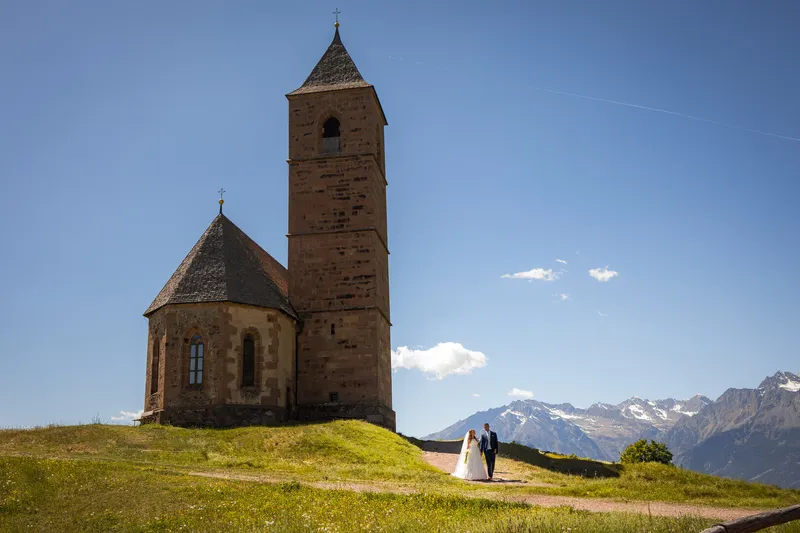 Ein Hochzeitspaar vor einer Bergkapelle in Südtirol