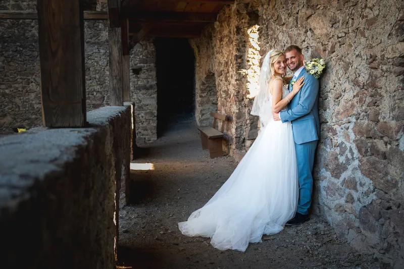 Ein Hochzeitspaar umarmt sich an einer rustikalen Steinmauer